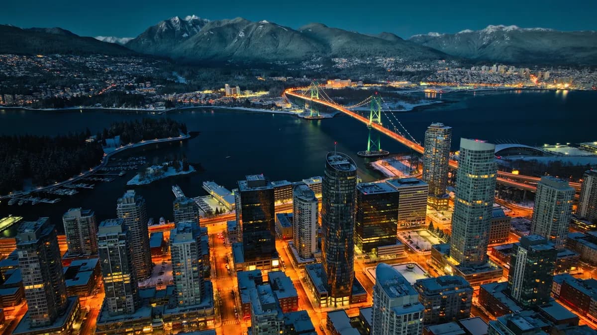 Aerial view of Vancouver at night with the Lions Gate Bridge and snow on the North Shore mountains