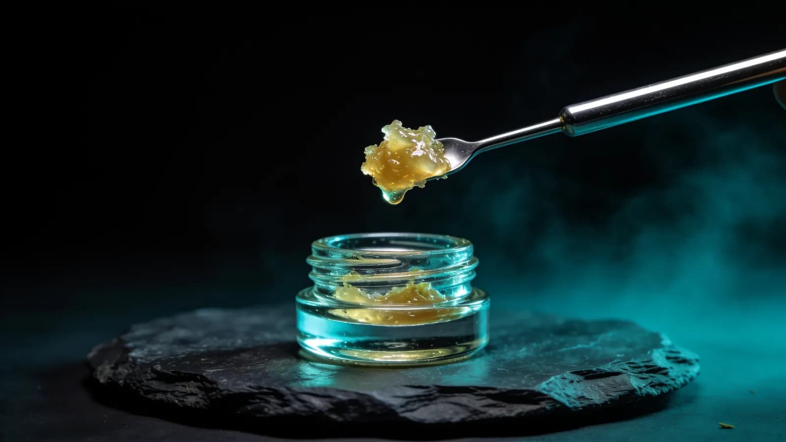 Golden live resin cannabis concentrate lifted on a dab tool above a glass jar
