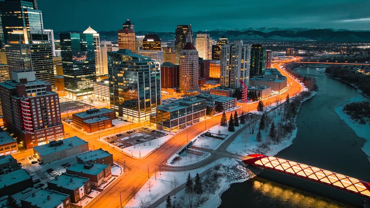 Aerial view of downtown Calgary at night with the red Peace Bridge over the Bow River