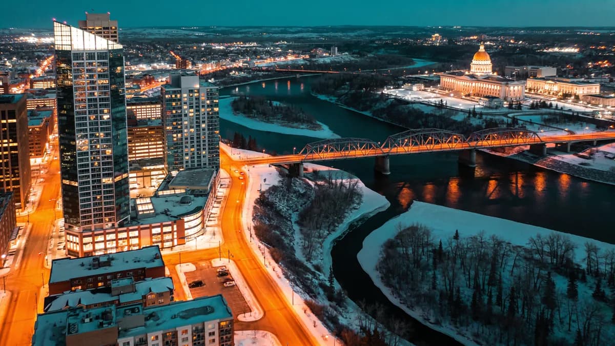 Aerial view of Edmonton at night with the river valley, a lit bridge and the Legislature dome