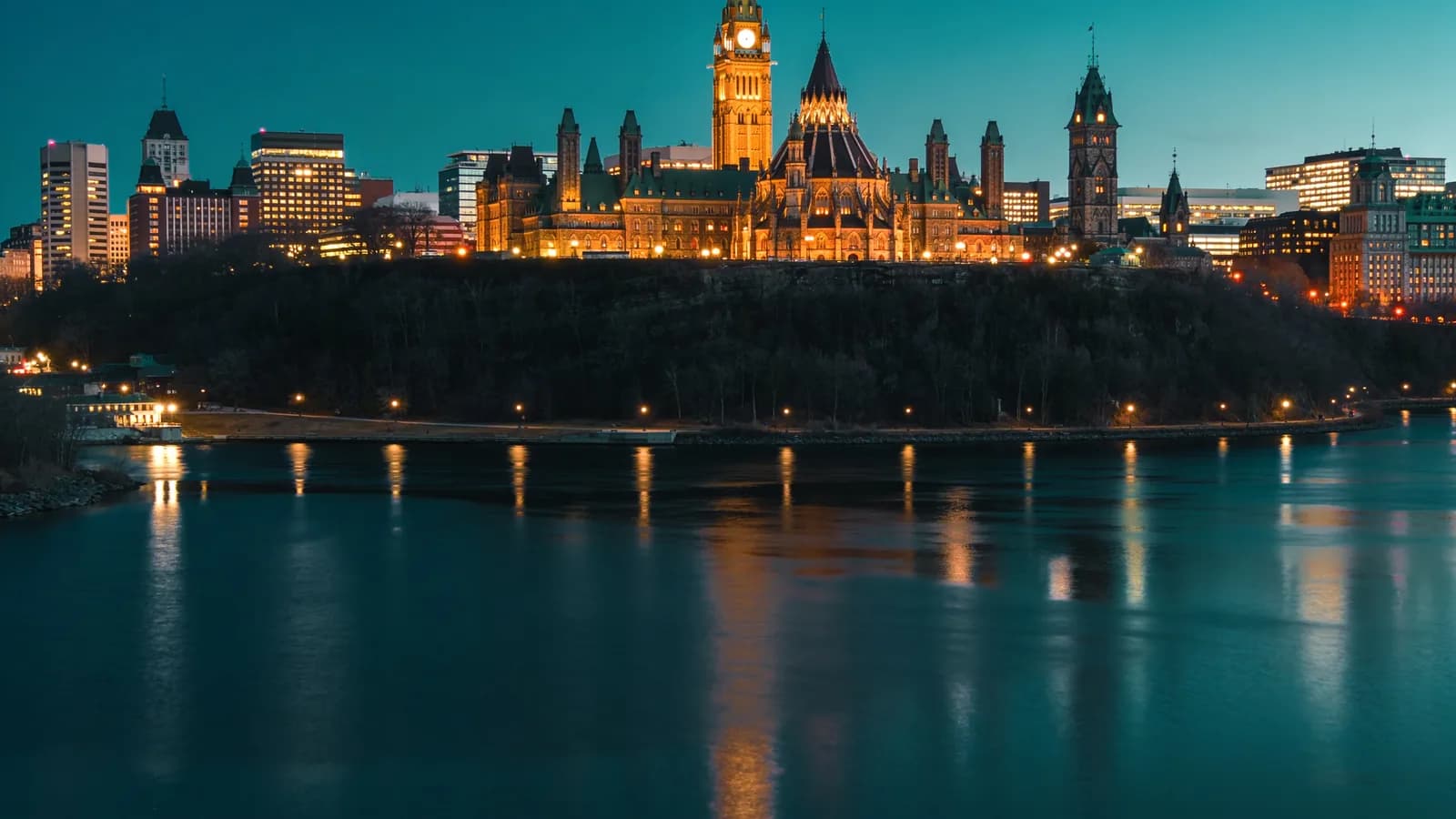Ottawa's Parliament buildings and Peace Tower at dusk above the Ottawa River